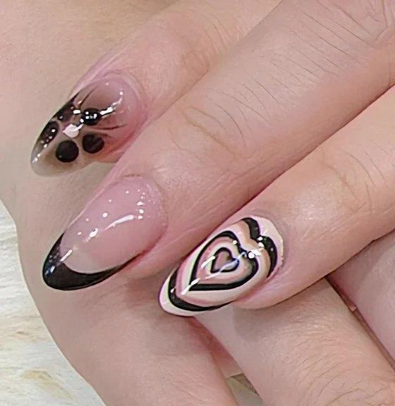 Nude almond nails with black French and painted hearts